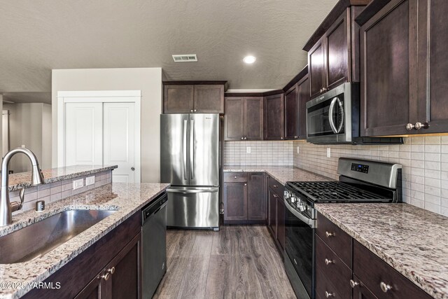 2201 S 62nd Ave, Yakima, WA 98903 - kitchen featuring appliances with stainless steel finishes, a sink, dark wood-style flooring, light stone countertops, and a textured ceiling