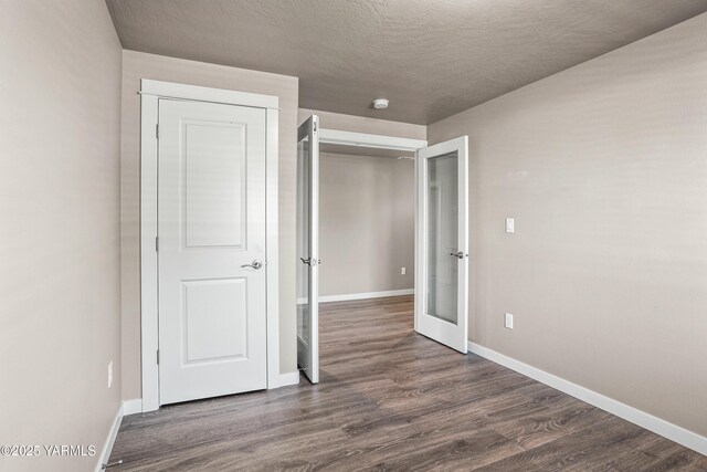2201 S 62nd Ave, Yakima, WA 98903 - unfurnished bedroom featuring baseboards, dark wood-style floors, french doors, and a textured ceiling