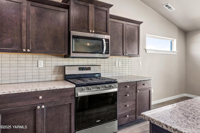 2201 S 62nd Ave, Yakima, WA 98903 - kitchen featuring appliances with stainless steel finishes, vaulted ceiling, light wood finished floors, backsplash, and dark brown cabinetry
