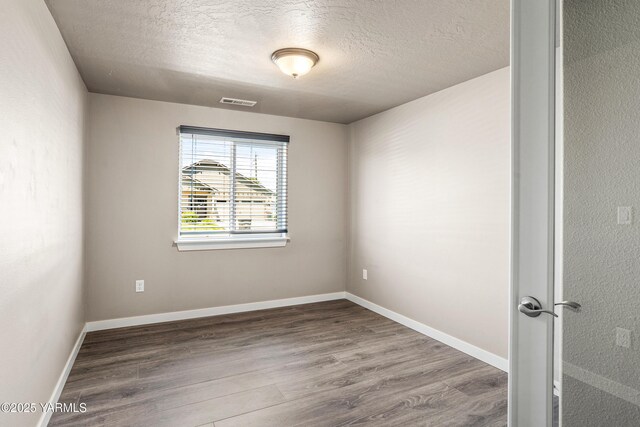 2201 S 62nd Ave, Yakima, WA 98903 - spare room featuring a textured ceiling, wood finished floors, and baseboards