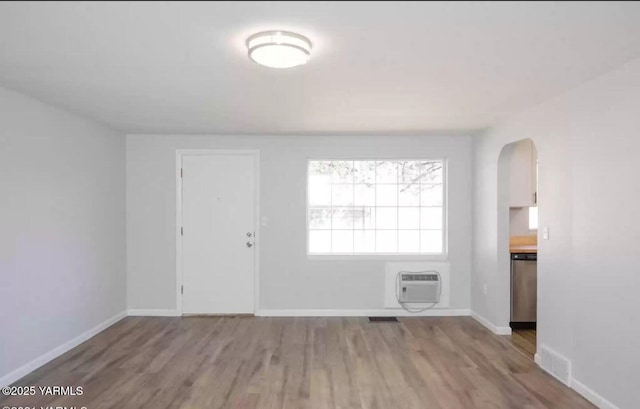 unfurnished room with baseboards, wood finished floors, and a wall mounted AC