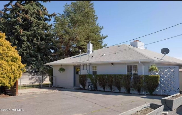 ranch-style home with a chimney and fence