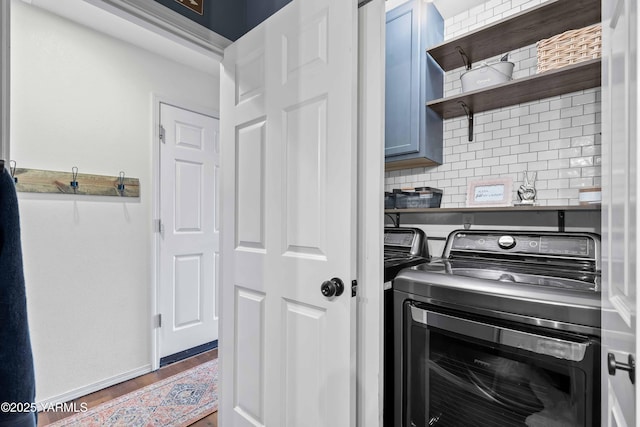 laundry room with wood finished floors, baseboards, cabinet space, and washing machine and dryer