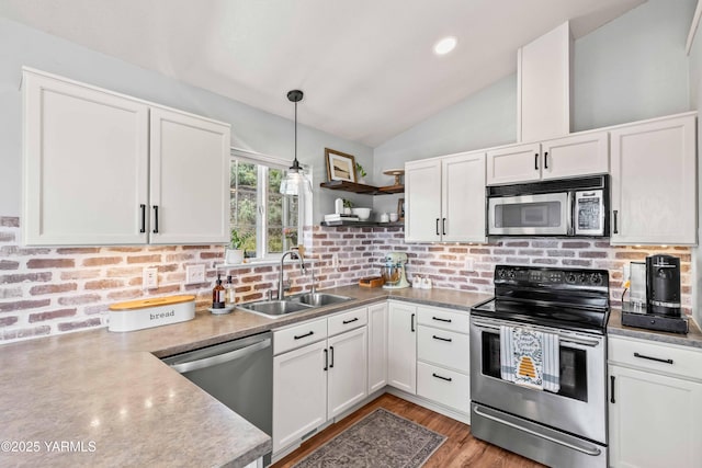 kitchen with decorative backsplash, appliances with stainless steel finishes, open shelves, vaulted ceiling, and a sink