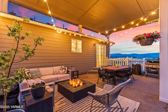view of patio / terrace featuring an outdoor living space with a fire pit, a mountain view, outdoor dining area, and grilling area