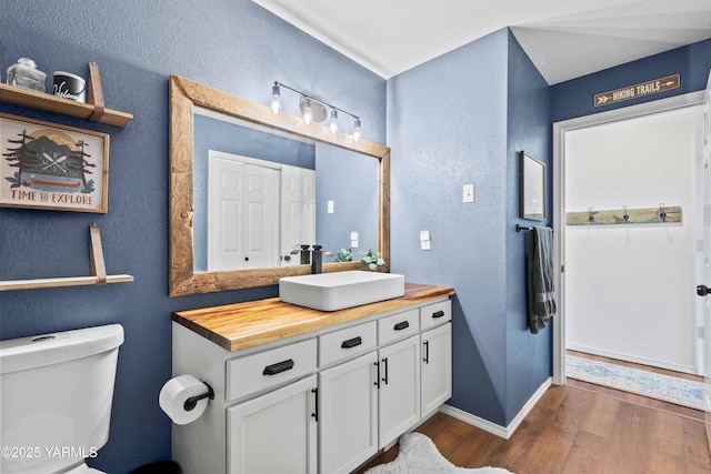 bathroom with baseboards, a textured wall, wood finished floors, and vanity
