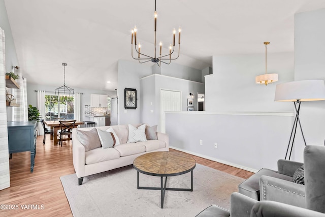 living room featuring vaulted ceiling, light wood-style flooring, and a notable chandelier