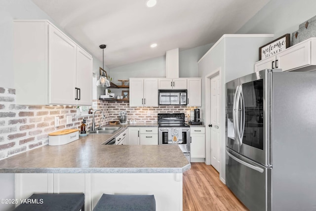 kitchen with appliances with stainless steel finishes, open shelves, a sink, a peninsula, and lofted ceiling