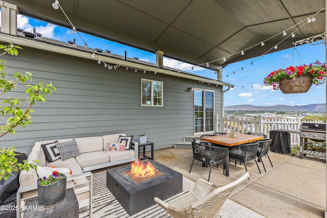 view of patio / terrace featuring outdoor dining area, an outdoor living space with a fire pit, a mountain view, and a grill