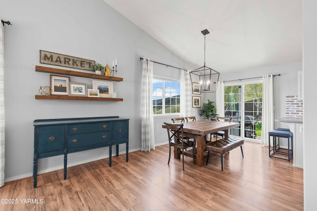 dining space with an inviting chandelier, light wood finished floors, and lofted ceiling