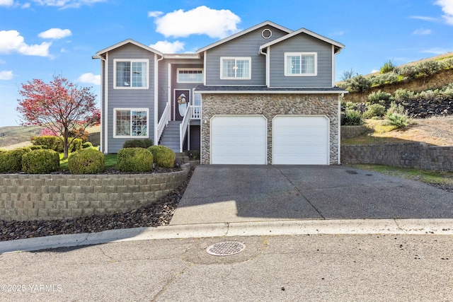 split foyer home featuring stairs, a garage, stone siding, and concrete driveway
