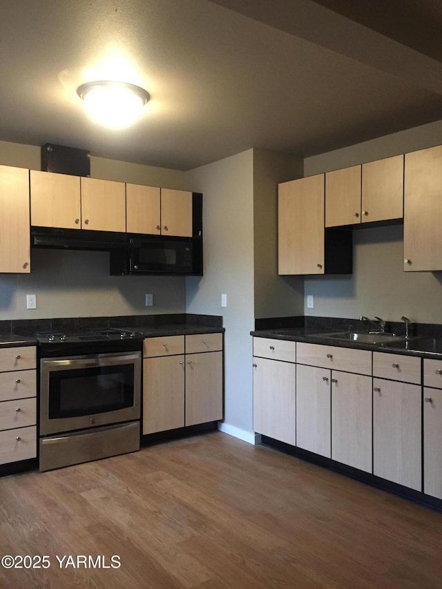 kitchen featuring dark countertops, light brown cabinets, and stainless steel electric range