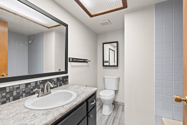 bathroom with visible vents, a shower, vanity, and toilet