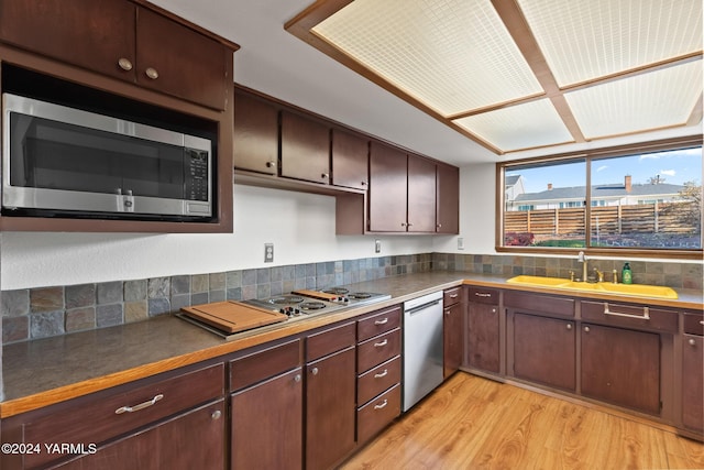 kitchen featuring dark countertops, stainless steel appliances, dark brown cabinets, and light wood-type flooring