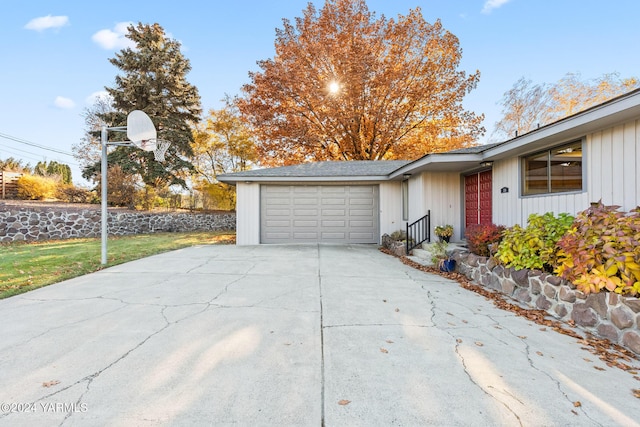 view of side of property with an attached garage, fence, and concrete driveway