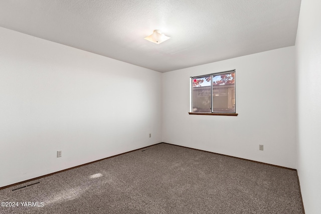 carpeted spare room featuring visible vents, a textured ceiling, and baseboards