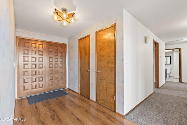 entryway featuring an inviting chandelier, baseboards, visible vents, and wood finished floors