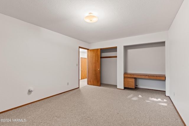 unfurnished bedroom featuring carpet floors, a closet, baseboards, and a textured ceiling