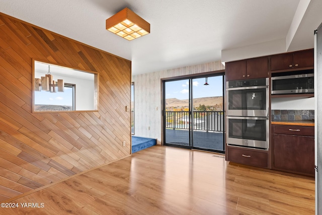 kitchen featuring a mountain view, stainless steel appliances, dark brown cabinets, light wood-type flooring, and decorative light fixtures