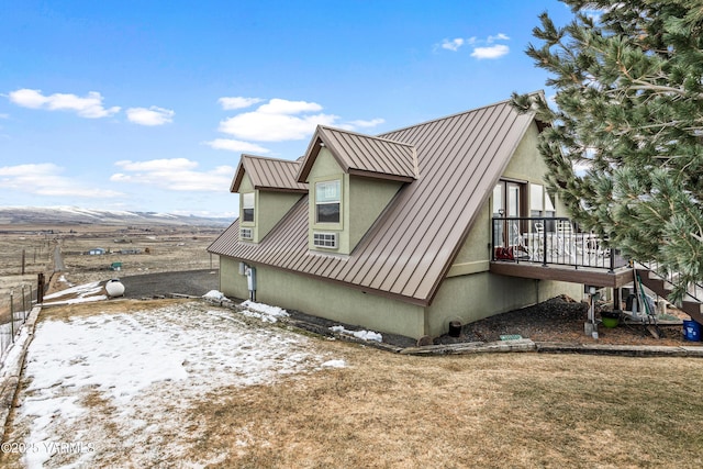 view of side of home featuring a standing seam roof, metal roof, and stucco siding