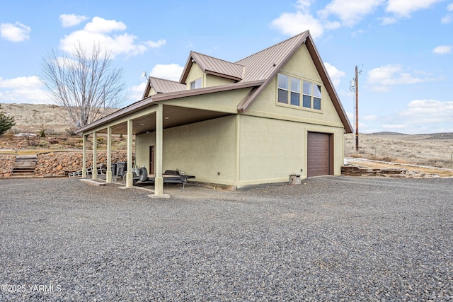 view of side of property featuring a garage, metal roof, and stucco siding