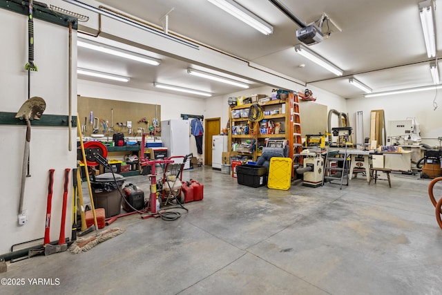 garage featuring a workshop area, freestanding refrigerator, and a garage door opener