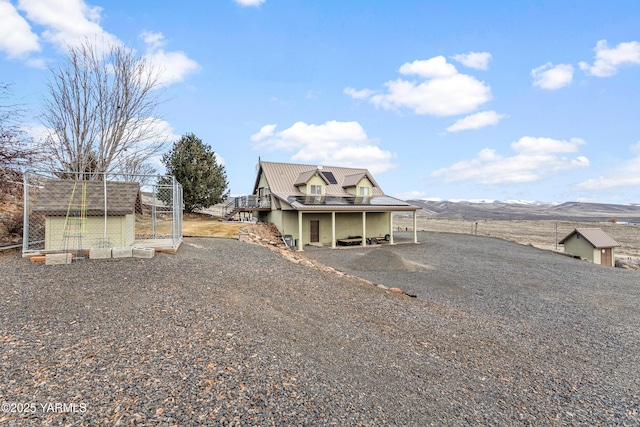 back of house with a deck with mountain view, driveway, stairway, and metal roof