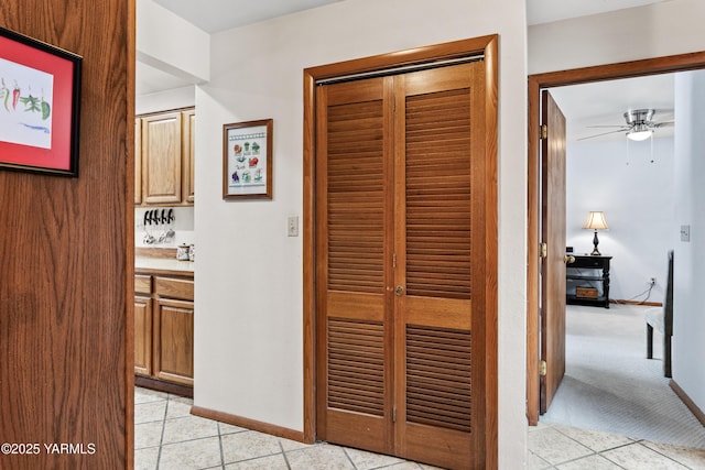 hall with light carpet, light tile patterned floors, and baseboards