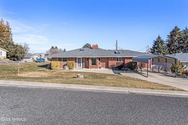 view of front of property featuring a carport, a front lawn, concrete driveway, and brick siding