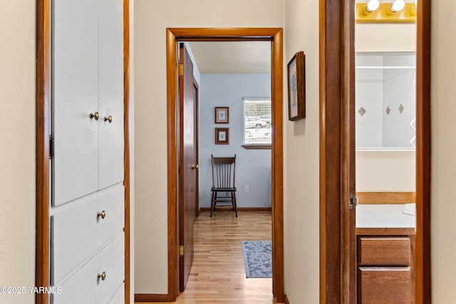 hallway with light wood-type flooring and baseboards