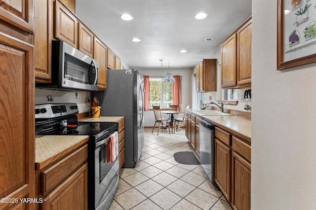 kitchen featuring stainless steel appliances, light tile patterned flooring, a sink, and light countertops