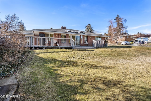 rear view of house with a yard, brick siding, a chimney, and a wooden deck