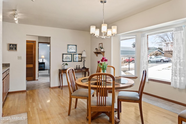 dining area with light wood finished floors, baseboards, and a notable chandelier