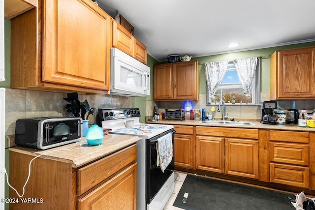 kitchen with white appliances, light countertops, a sink, and brown cabinetry