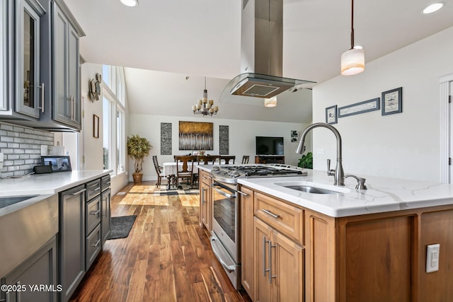 921 Tibbling Rd, Selah, WA 98942 - kitchen featuring island exhaust hood, gas range, wood finished floors, a kitchen island with sink, and decorative backsplash