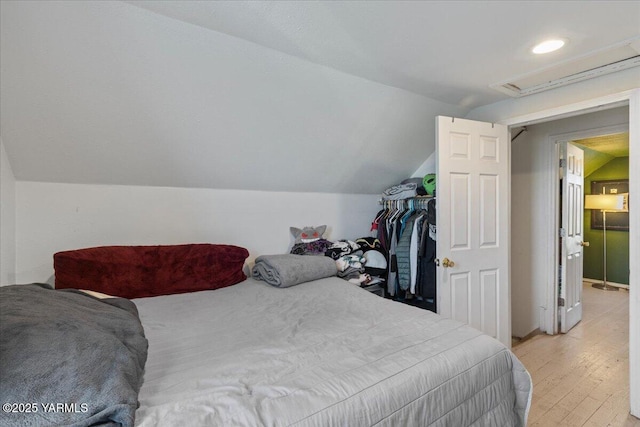 bedroom with attic access, light wood-type flooring, and lofted ceiling