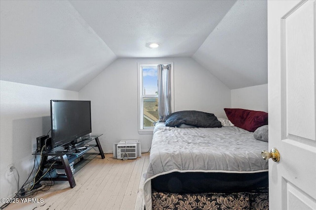 bedroom featuring a textured ceiling, hardwood / wood-style floors, and lofted ceiling
