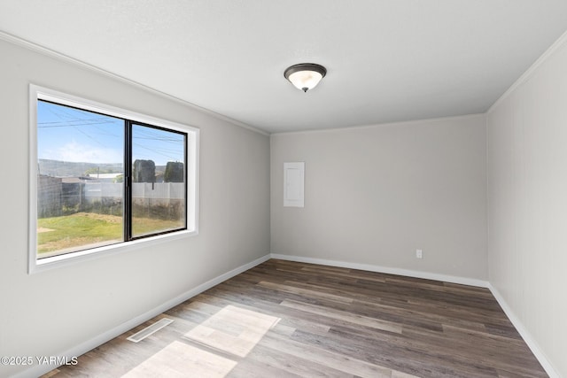 spare room featuring visible vents, baseboards, wood finished floors, and ornamental molding