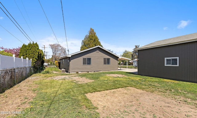 back of house with central air condition unit, fence, and a yard