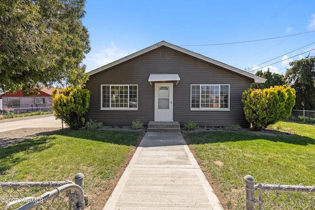 bungalow featuring fence and a front lawn