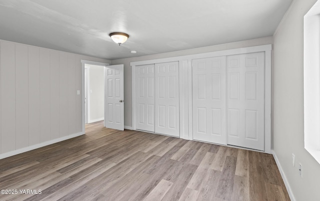 unfurnished bedroom featuring wood finished floors, multiple closets, and baseboards