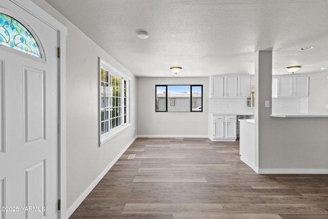 interior space with baseboards, wood finished floors, and a textured ceiling