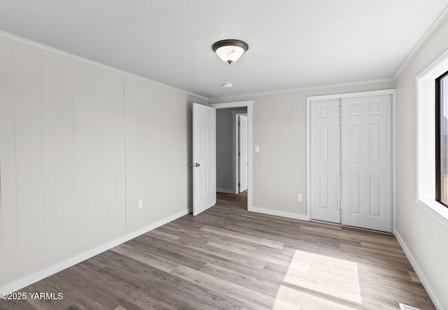 unfurnished bedroom with wood finished floors, crown molding, and multiple windows