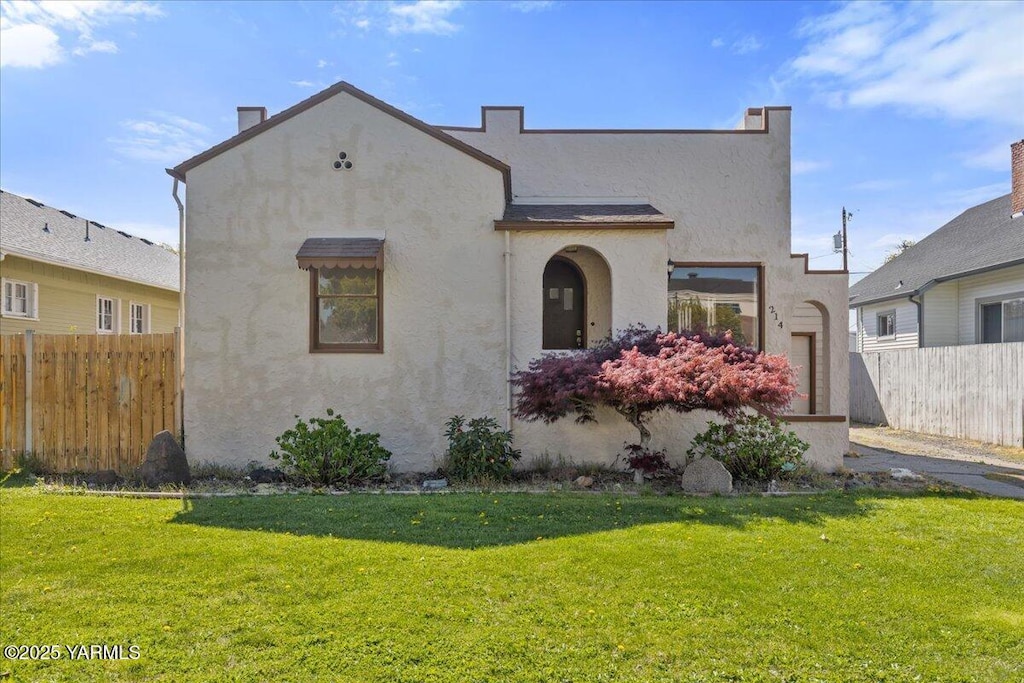 mediterranean / spanish-style house featuring stucco siding, a front lawn, and fence