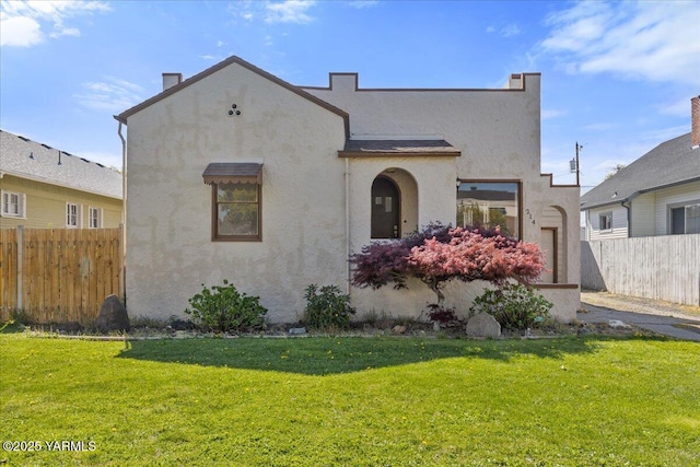 mediterranean / spanish-style house featuring stucco siding, a front lawn, and fence