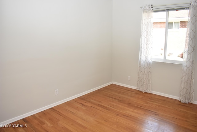 spare room with baseboards and light wood-style floors