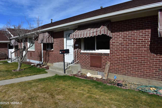 exterior space with brick siding and a front yard