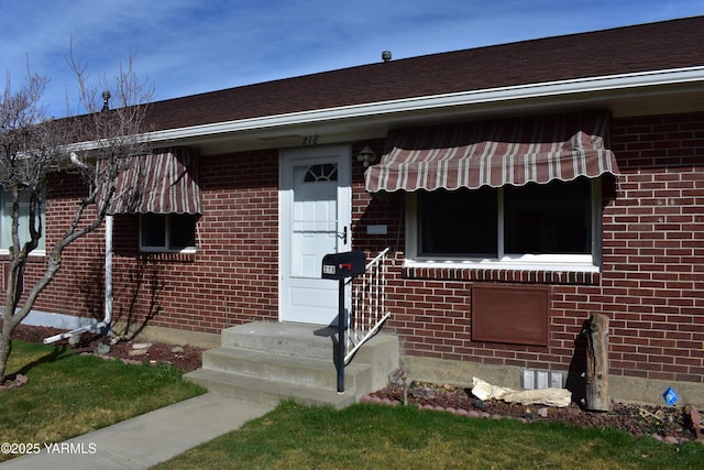 property entrance featuring brick siding and a shingled roof