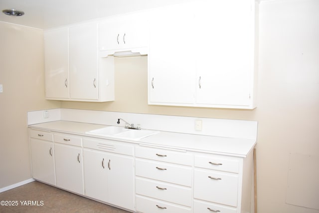 kitchen with a sink, white cabinetry, and light countertops