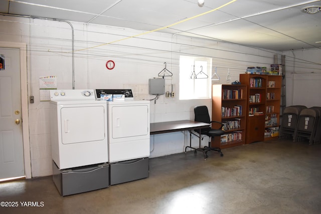 washroom featuring concrete block wall, laundry area, and washer and clothes dryer